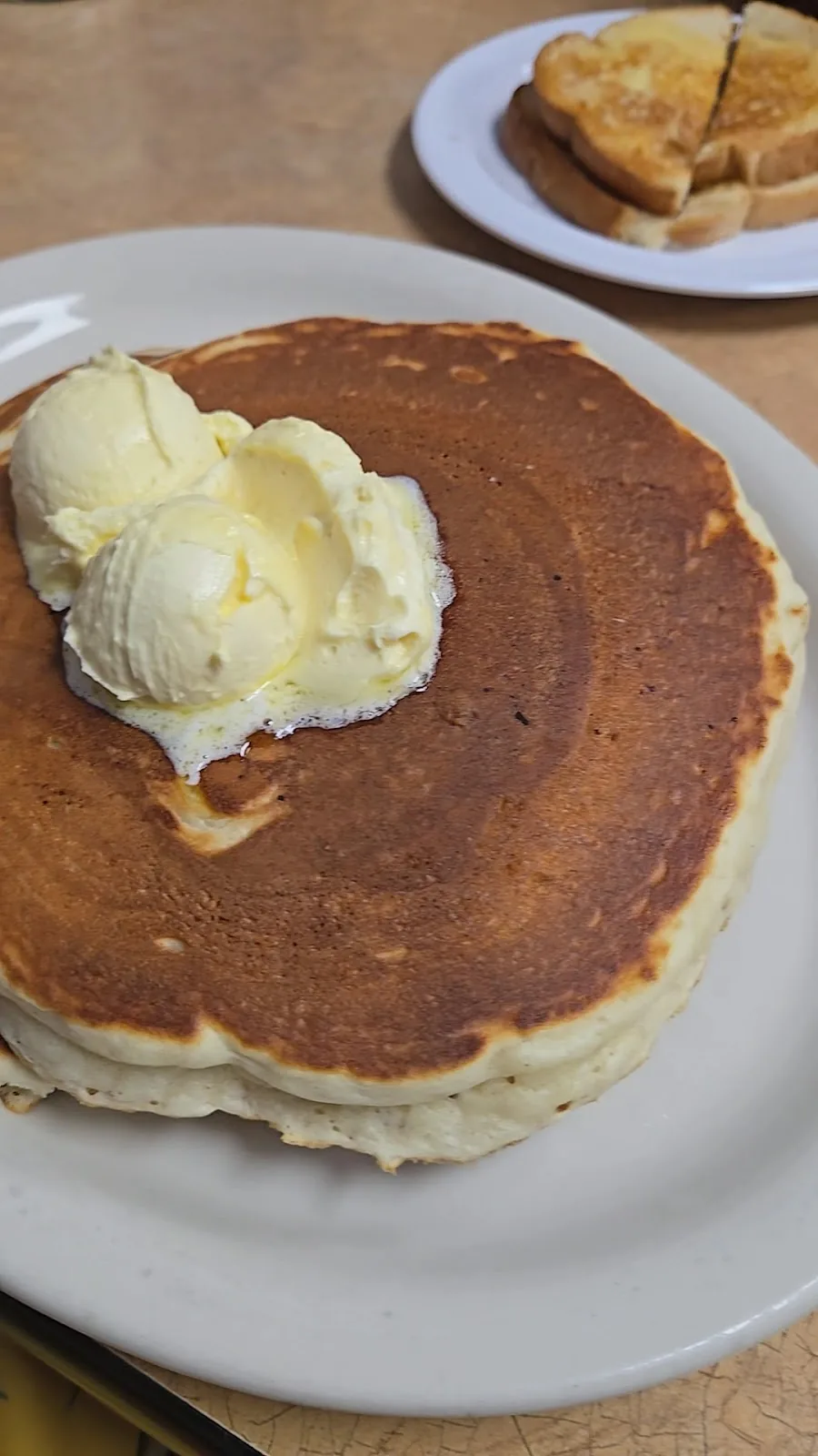 A large griddled pancake topped with butter, served with toast at City Cafe in South Houston